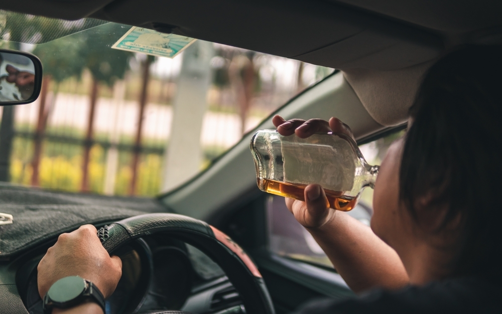 Man-drinking-alcohol-while-driving-in-his-car